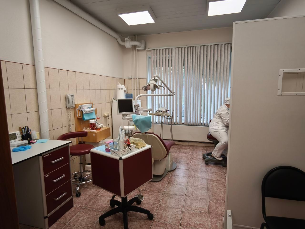 Dental treatment room with chair, instruments, and fluorescent lighting