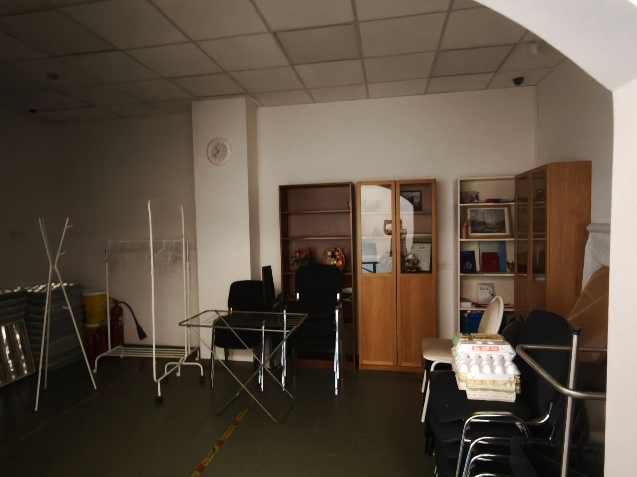 Dim room with drying racks, chairs, and cabinets arranged like a lounge or storage area