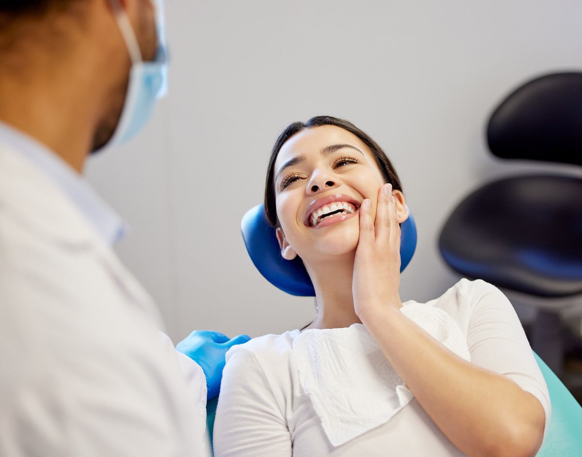 Dentist with blue gloves talking to a smiling patient in a dental chair