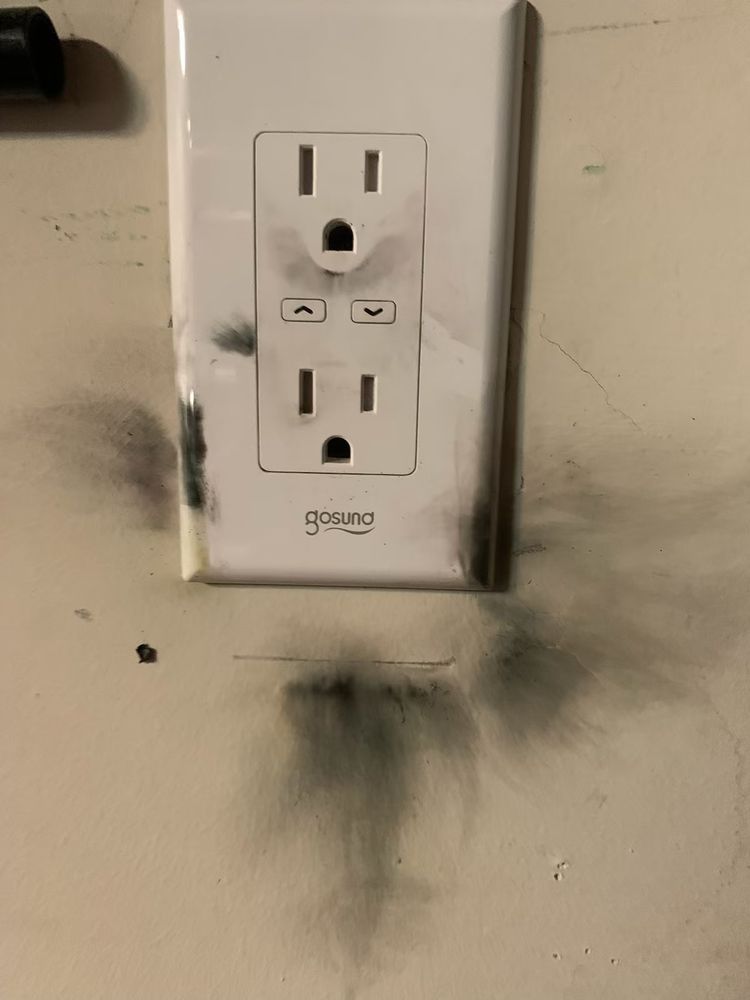 A white electrical outlet with smoke coming out of it.