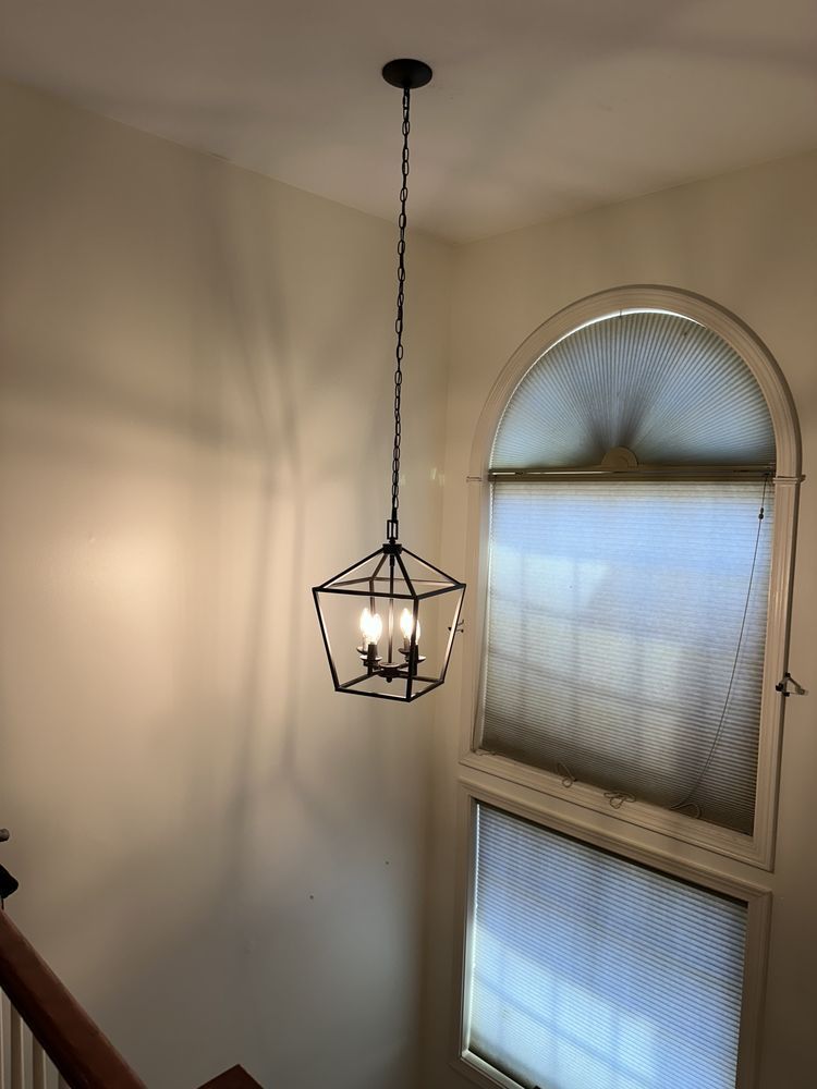 A chandelier is hanging from the ceiling in a room next to a window.