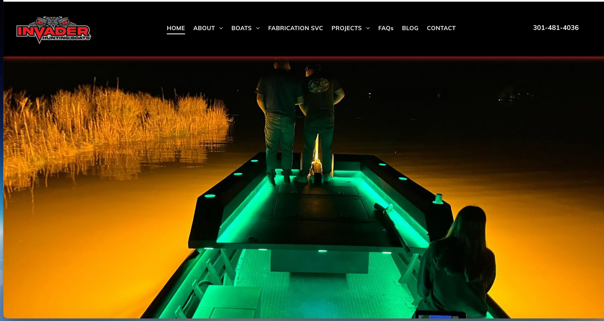A couple of people standing on the bow of an i invader hunting boat at night.