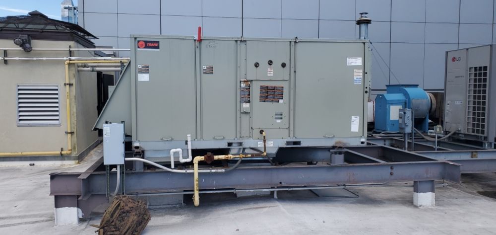 Rooftop HVAC unit on a metal frame, next to a smaller structure with a vent.