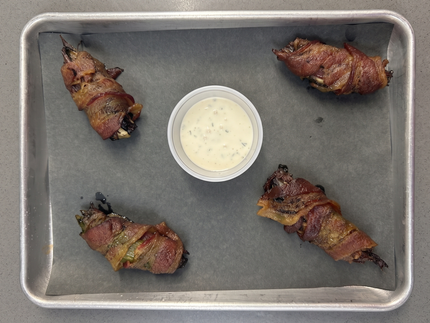 A wooden cutting board topped with chicken wings and celery sticks
