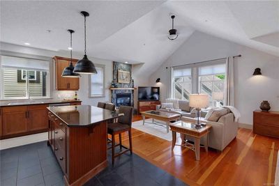 Open-concept kitchen and living area with a dark wood island, hardwood floors, fireplace, and a sofa.