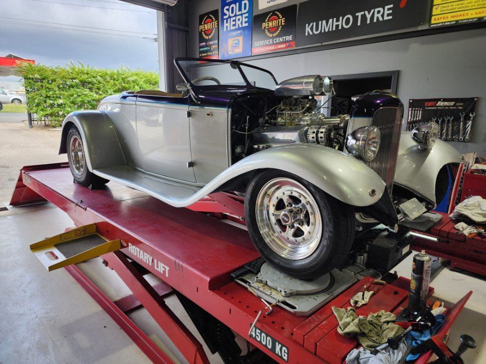 An Old Car is Sitting on a Red Lift in a Garage — All Care Car Services Kumho Tyre Platinum Dealer in Kurri Kurri, NSW