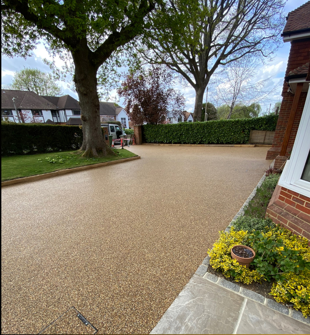 Four workers in navy uniforms inspecting a freshly paved driveway outside a brick house.