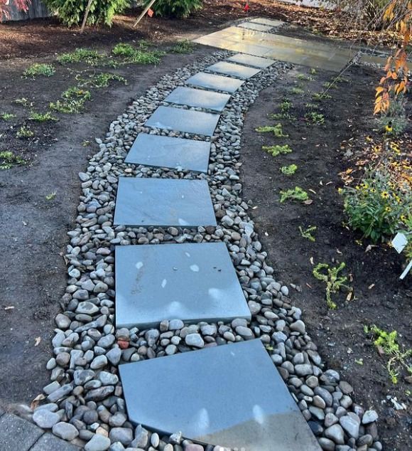 Bluestone stepping stone pathway with square stepping stones winding through a rock bed and garden.