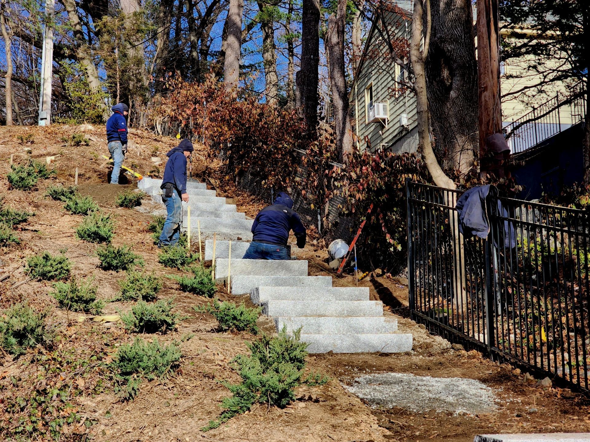 Granite Step Installation Landscapers building a stone stair way up a back yard slope in Winchester