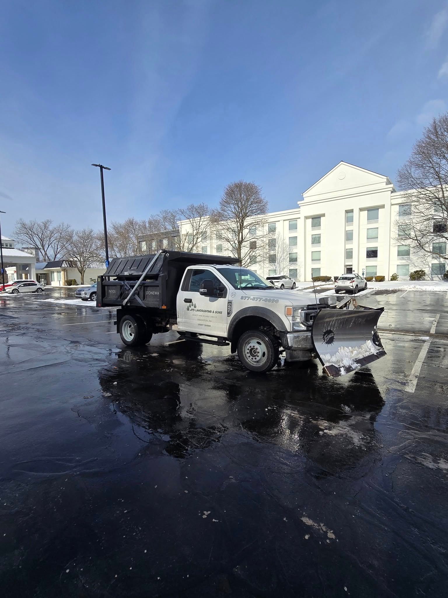 White snow plow truck parked on clear parking lot after a storm