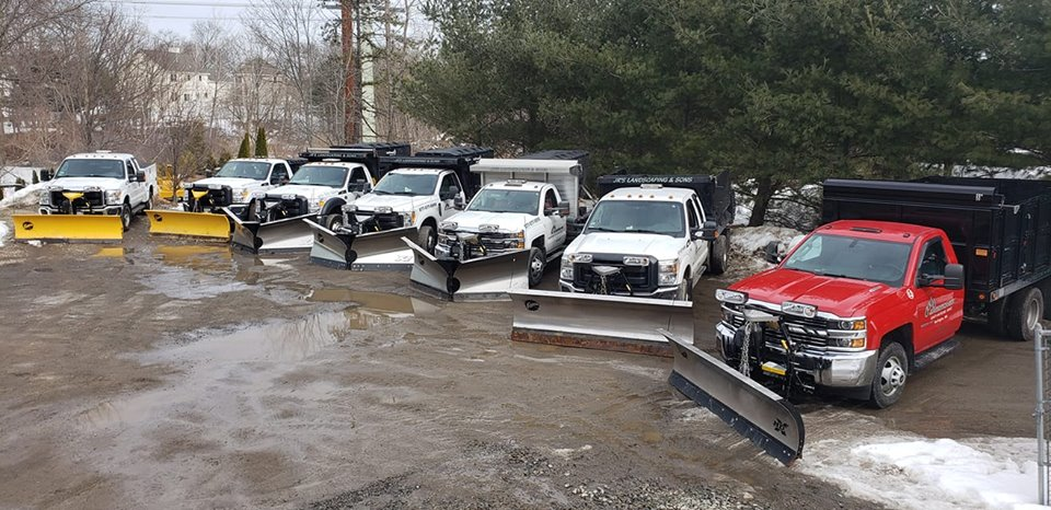 Commercial snow plowing fleet. Plows and salters on a row of trucks