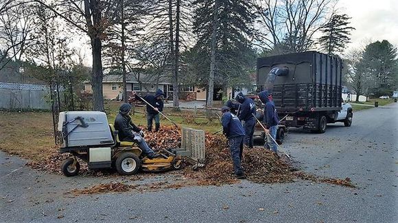 landscapers cleaning fall leaves from a yard.