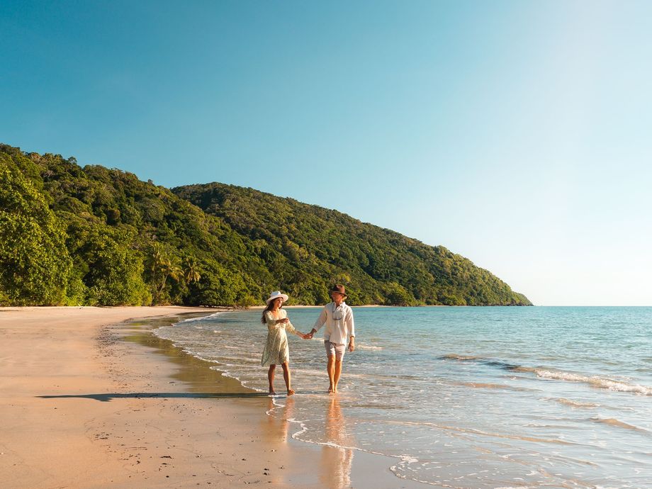 A couple enjoying their tour strolling along the waters edge at Cape Tribulation