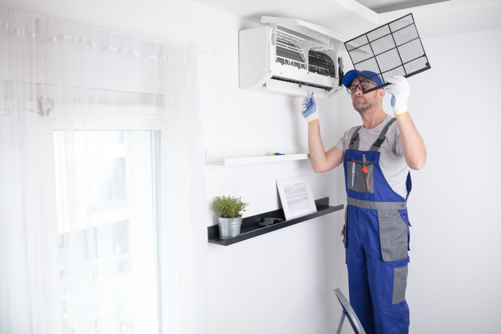 A man is fixing an air conditioner in a living room.