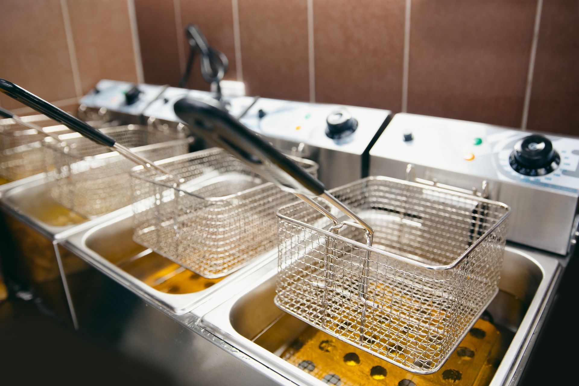 Three fryers are filled with oil in a kitchen.