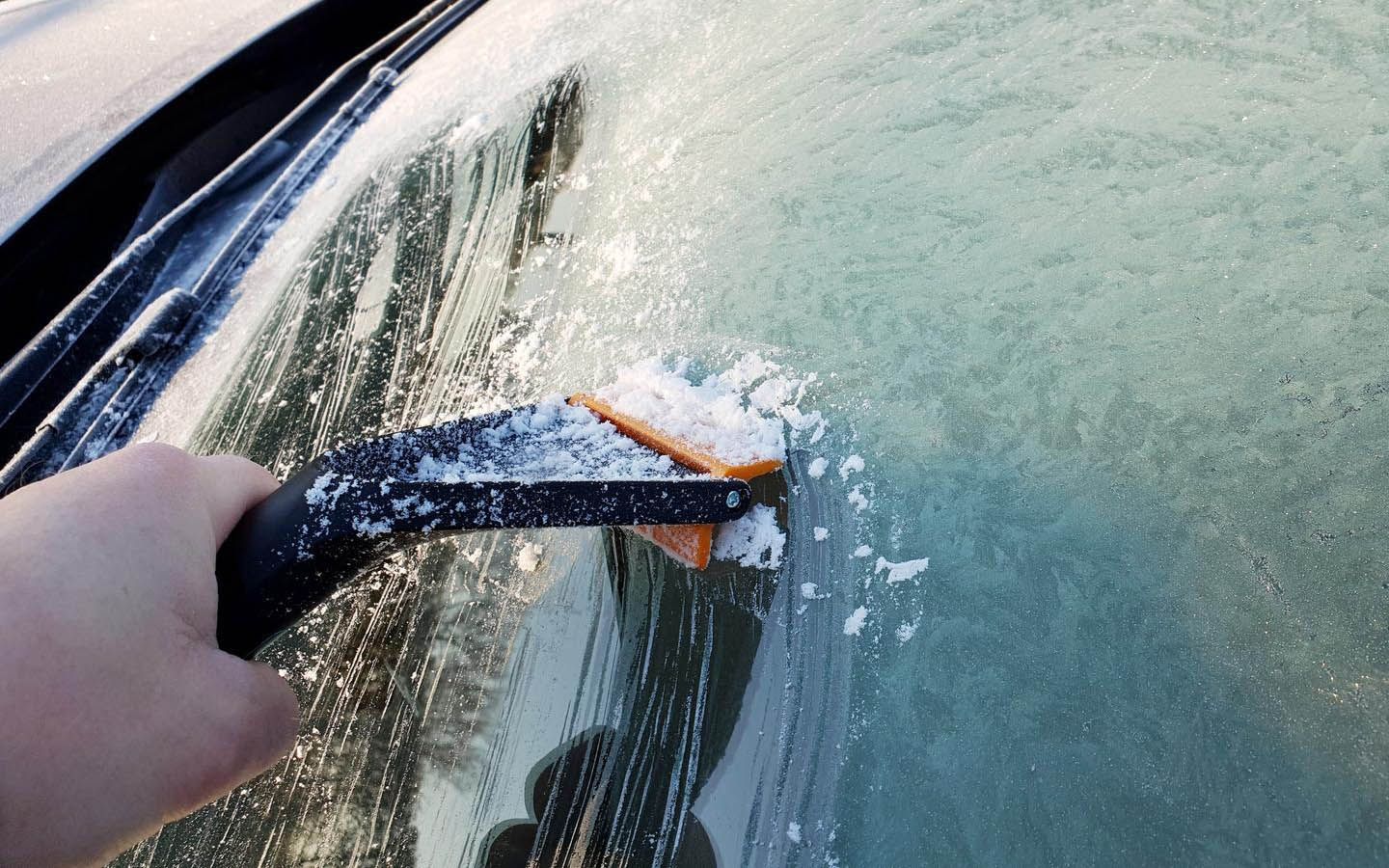 A person is deicing their windscreen