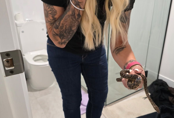 Sue holding a snake she has just captured in a bathroom