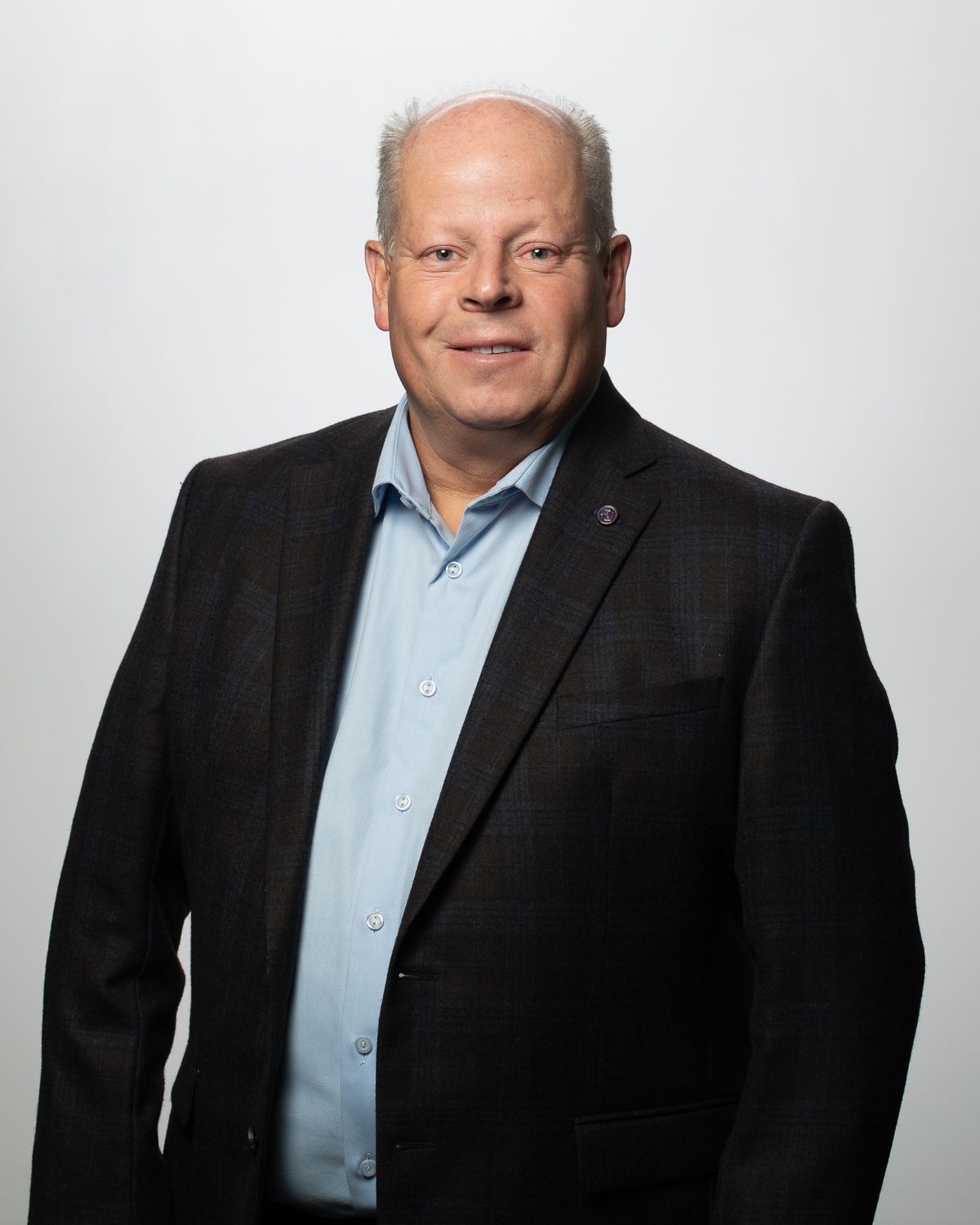 a man in a suit and blue shirt is smiling for the camera .