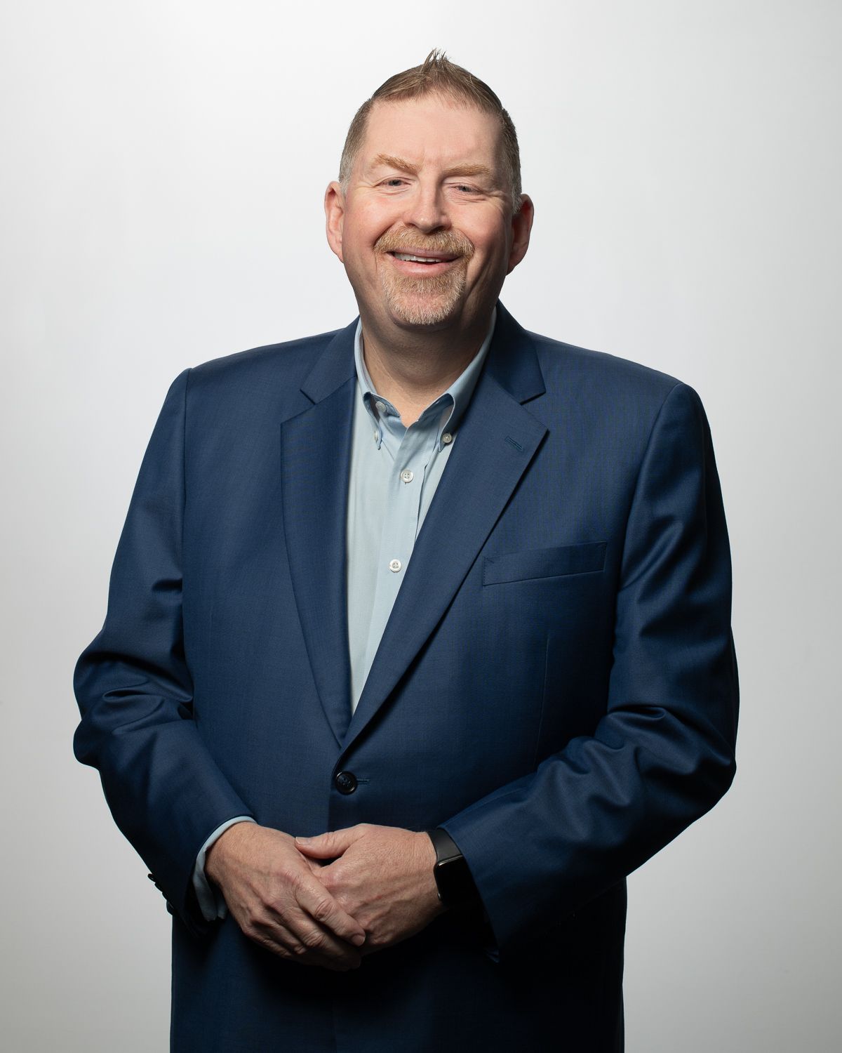 a man in a suit and blue shirt is smiling for the camera .