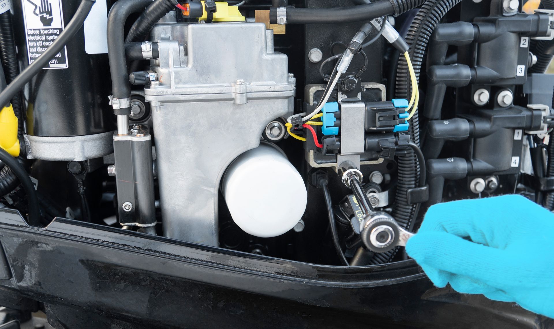 Blue-gloved hand adjusting a car engine component beside a white filter and silver housing.
