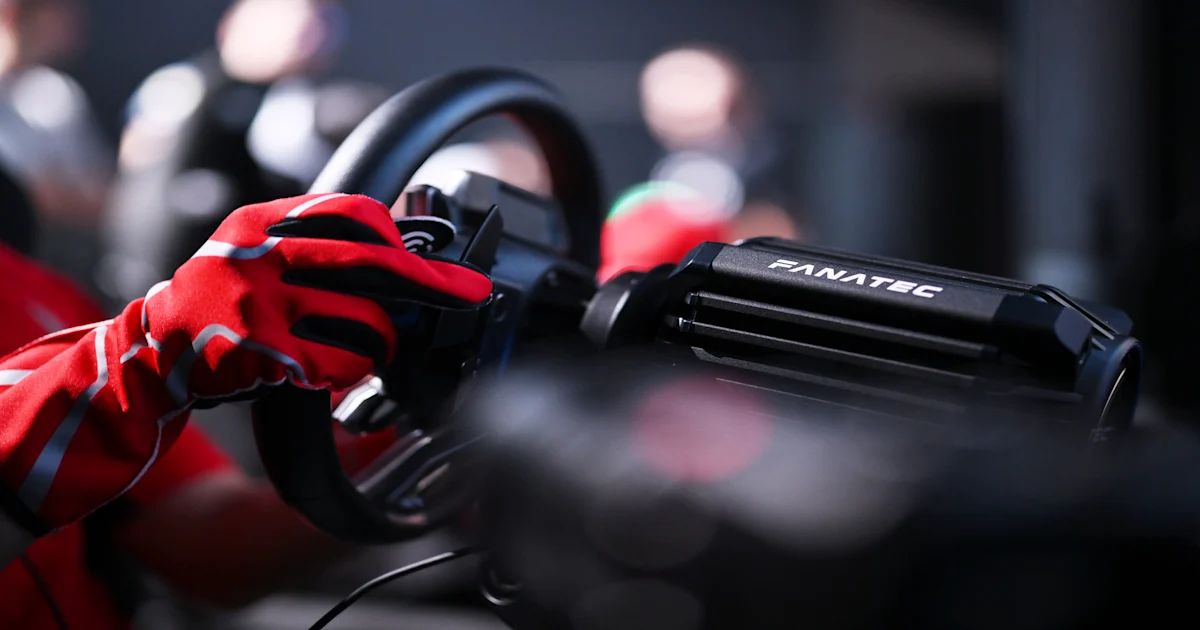 Red racing gloves gripping a steering wheel in a dark racing simulator cockpit