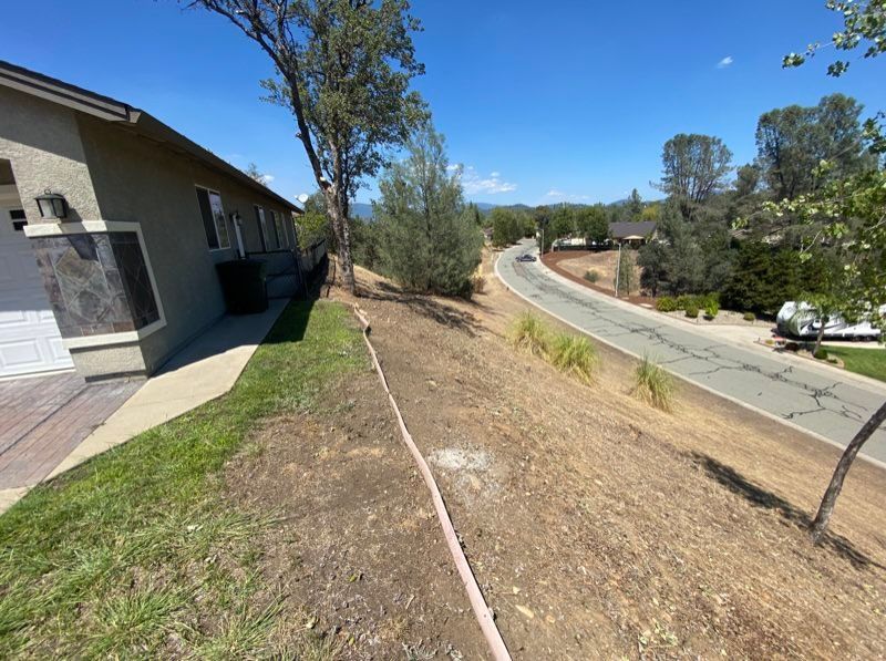 A house with a brown roof sits next to a long road on a sunny day.