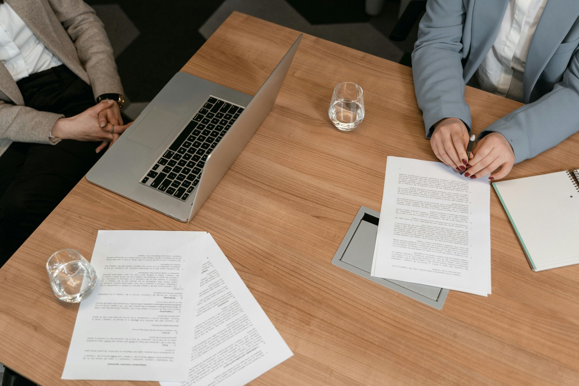 Two people are sitting at a table with papers and a laptop.