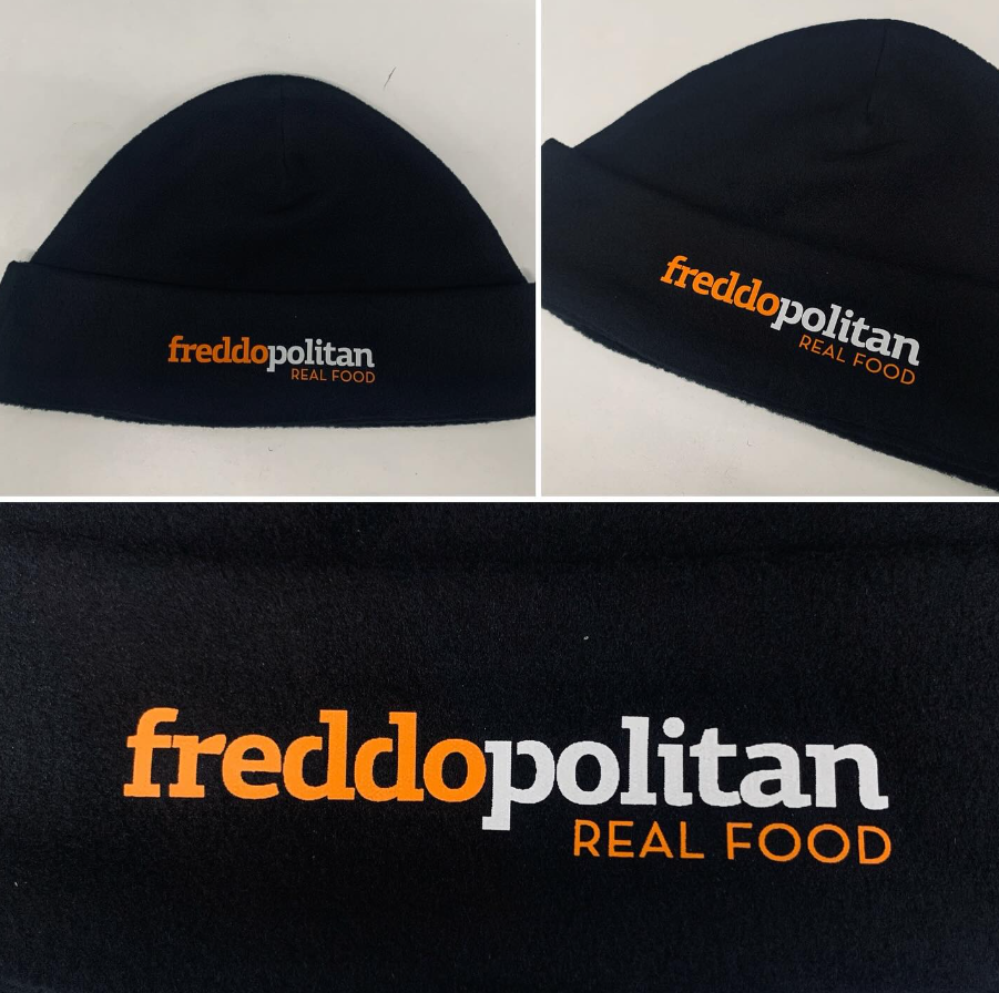 Ένα μαύρο καπέλο με τις λέξεις freddopolitan real food κεντημένες πάνω του