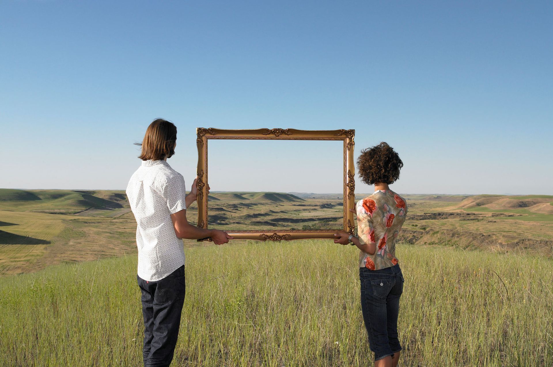 A man and woman holding a custom photo frame in an open land