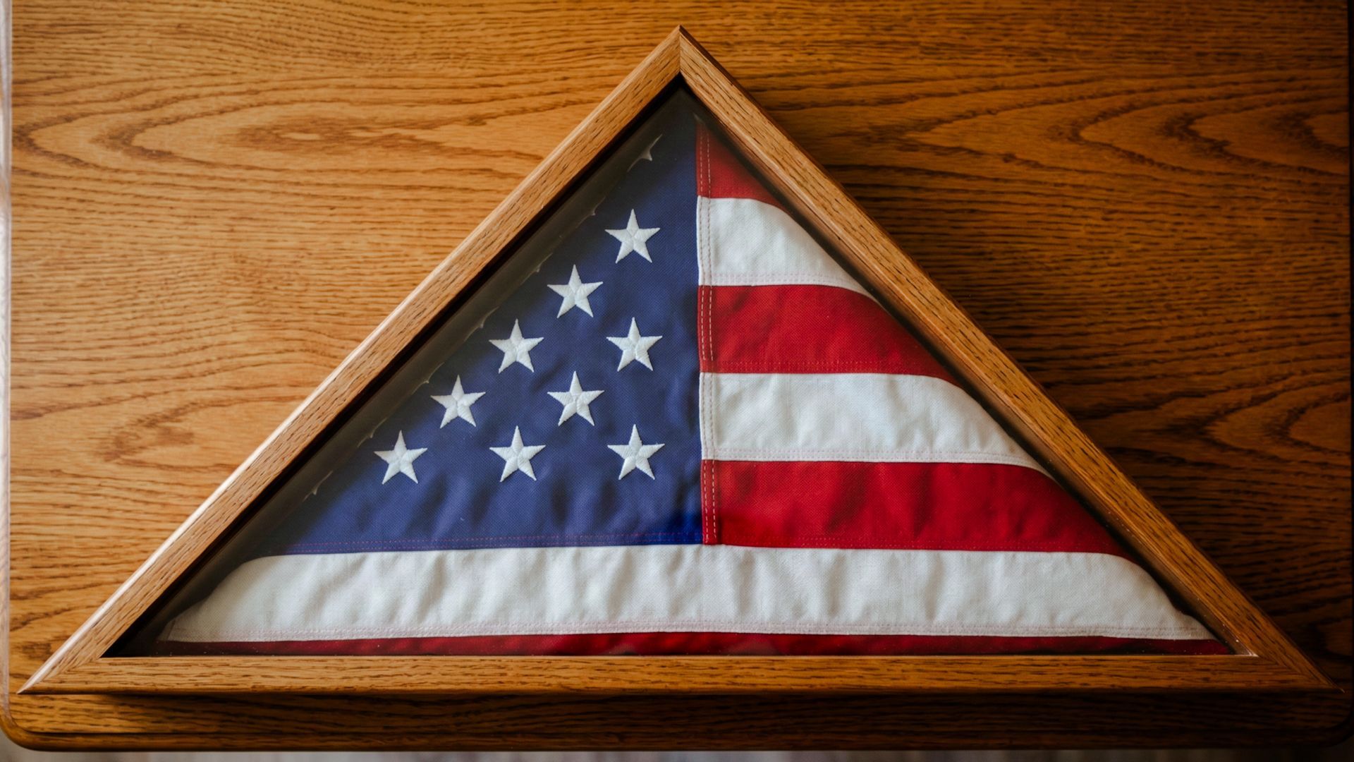 Folded American flag displayed inside a triangular shadow box
