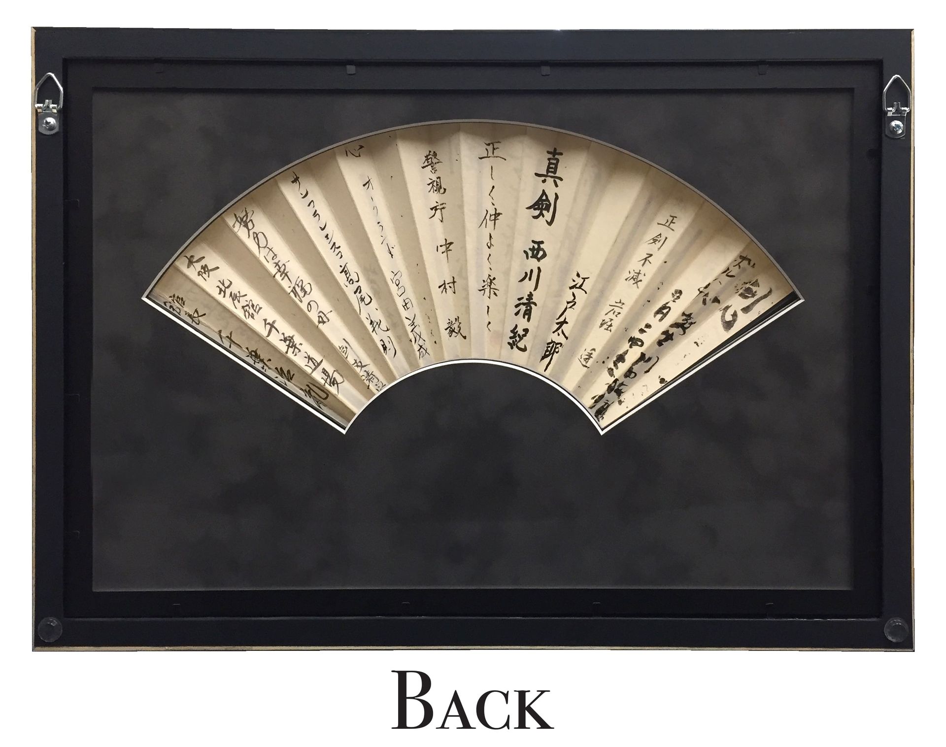 Black framed display holding a fan with calligraphy on a dark background.