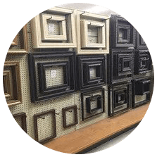 Frames of various sizes and colors displayed on a pegboard wall in a store.