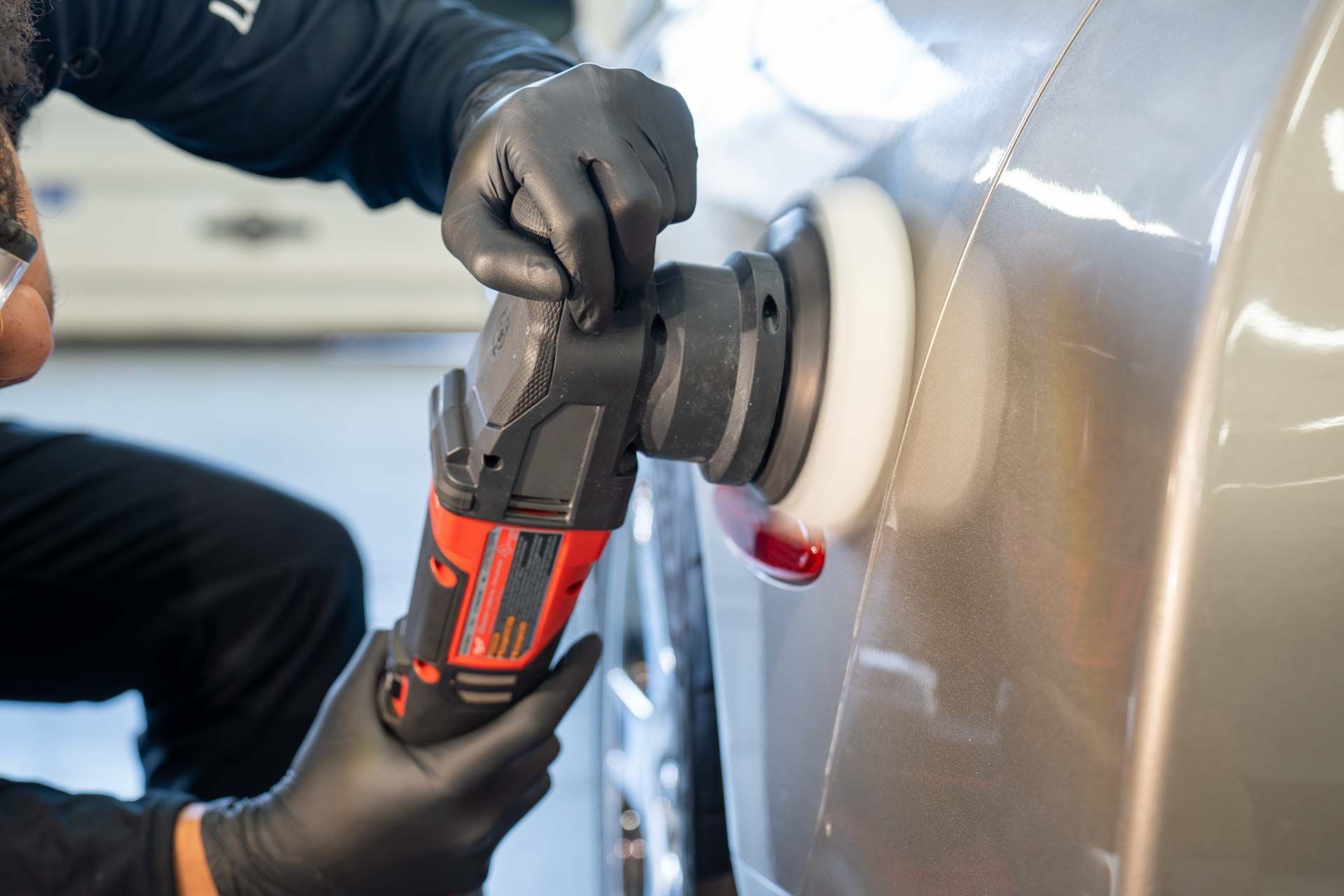 A man is polishing a car with a machine.