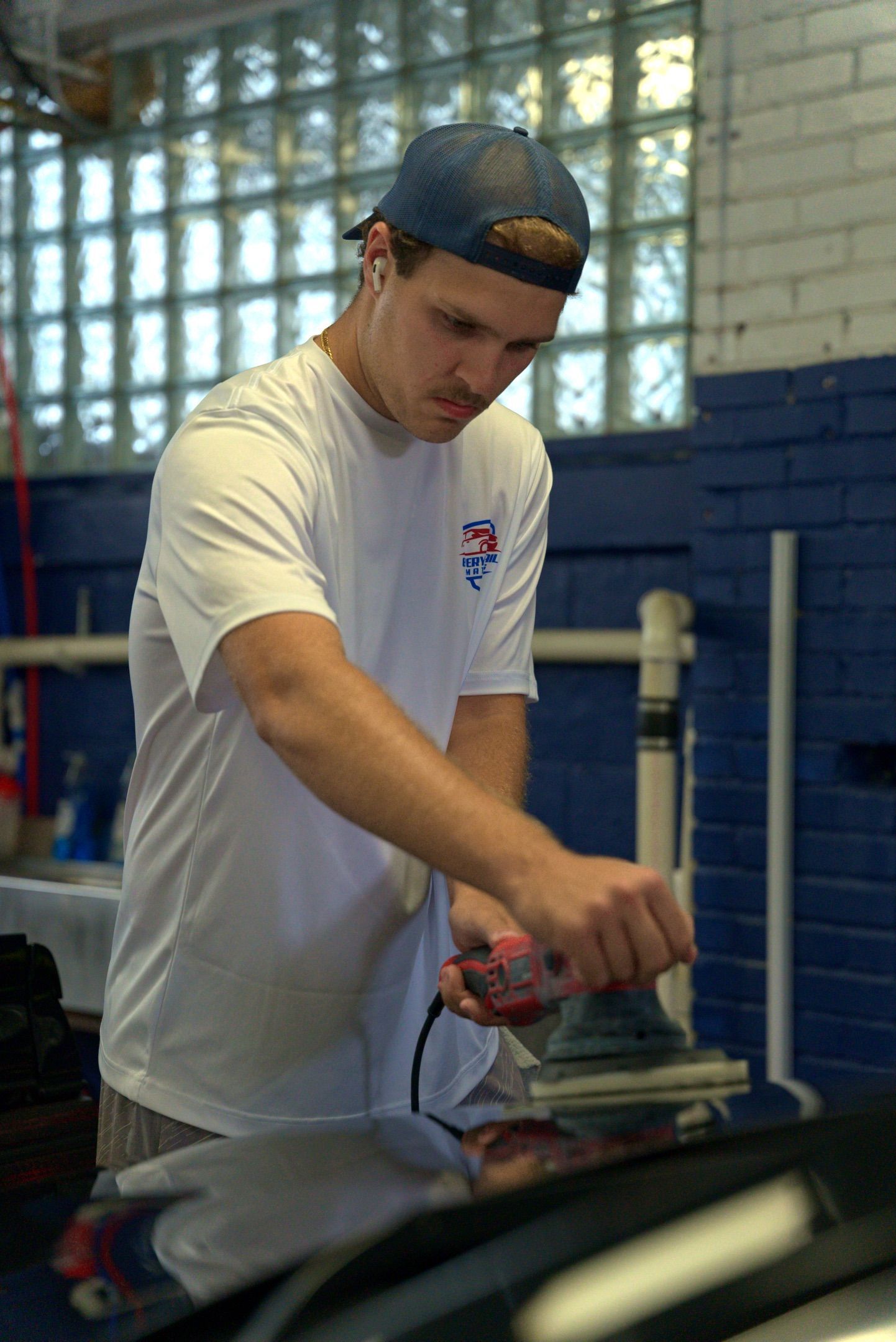 Man in a white T-shirt ironing clothing in a workshop with blue walls