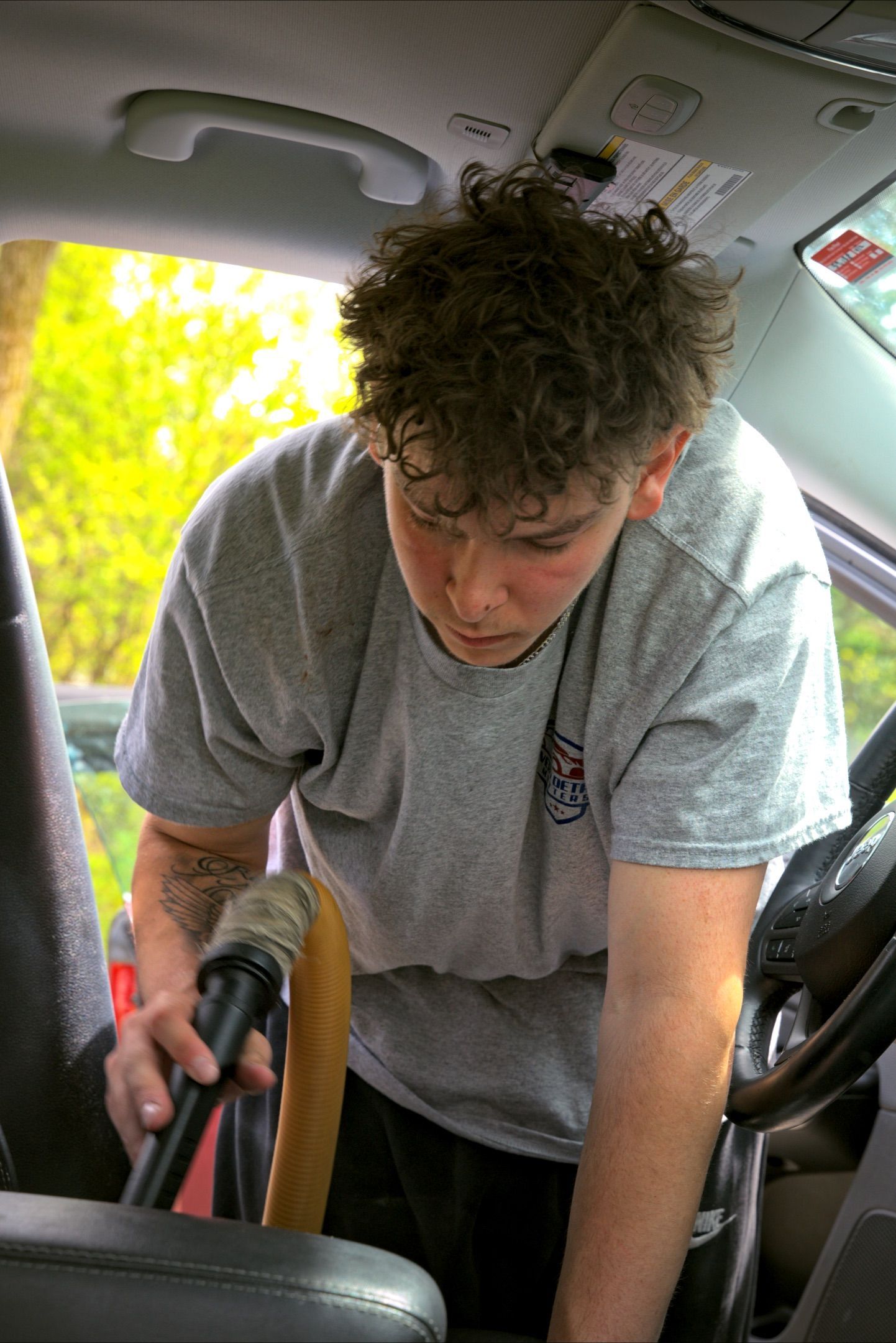 A man is cleaning the door of a car with a towel.