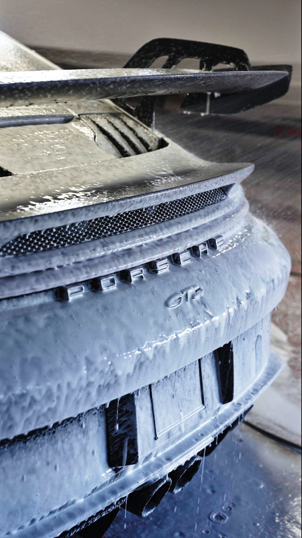 A frosted car bumper and hood covered in ice and snow, with a rear spoiler visible above.