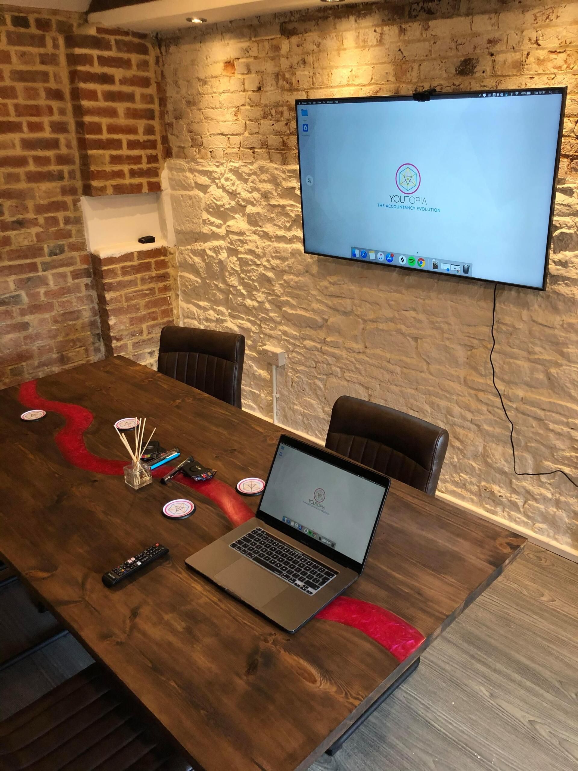 A laptop is sitting on a wooden table in a conference room.