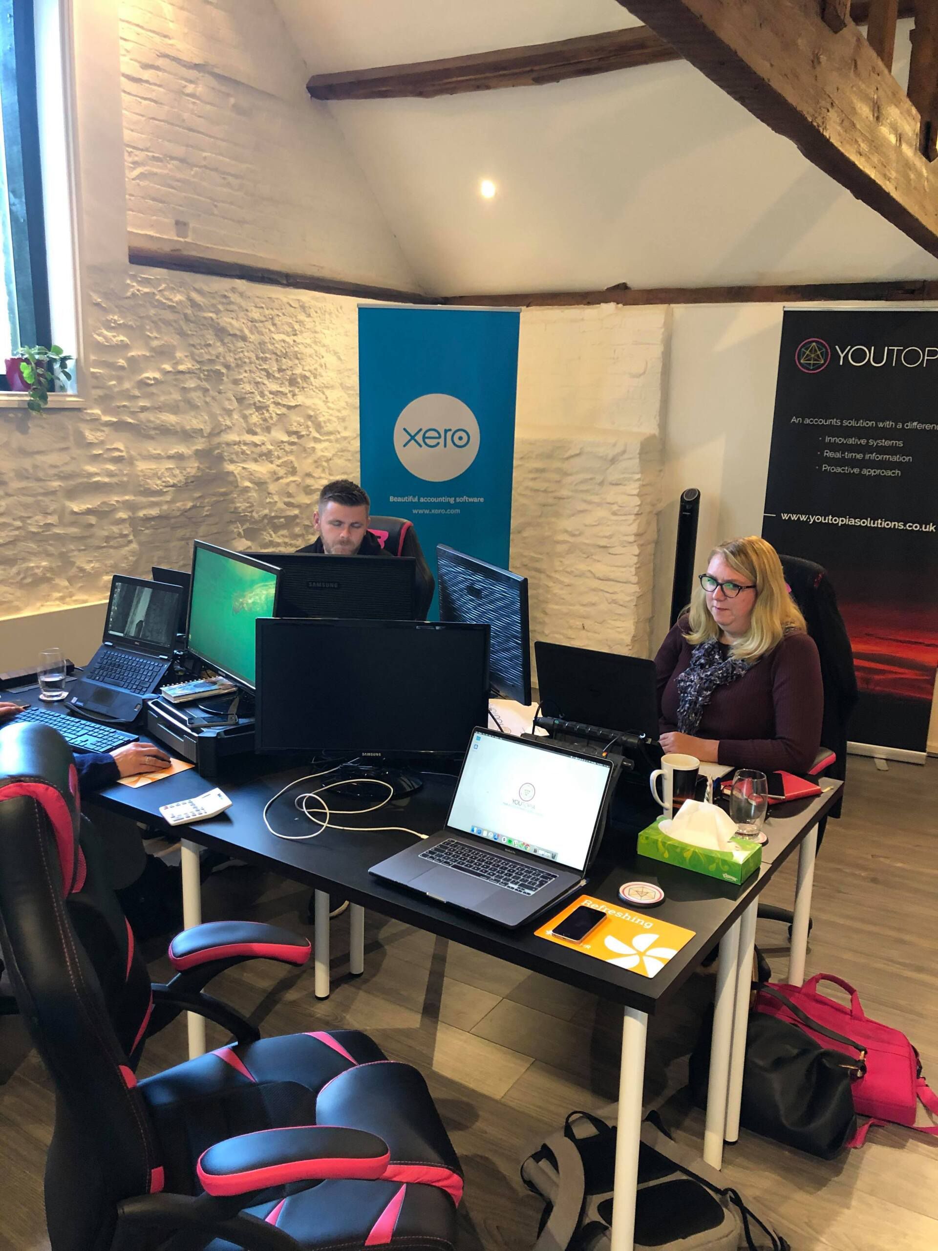 A group of people are sitting at desks in an office working on computers.
