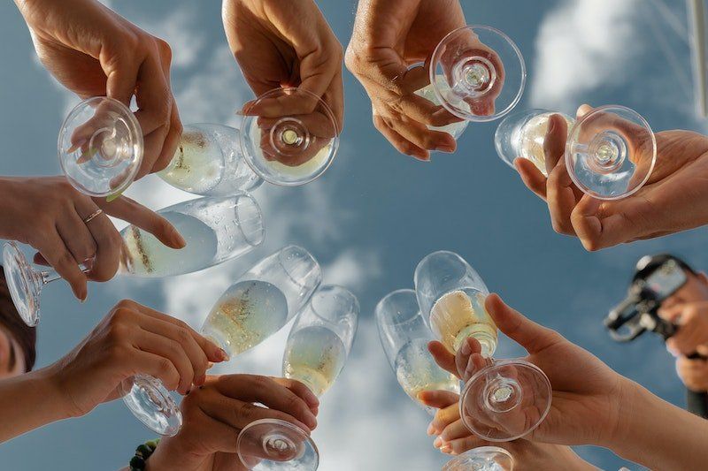 A group of people are holding champagne glasses in a circle.