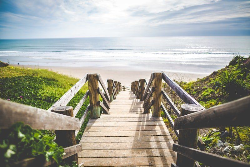 A wooden bridge leading to a beach with a view of the ocean.