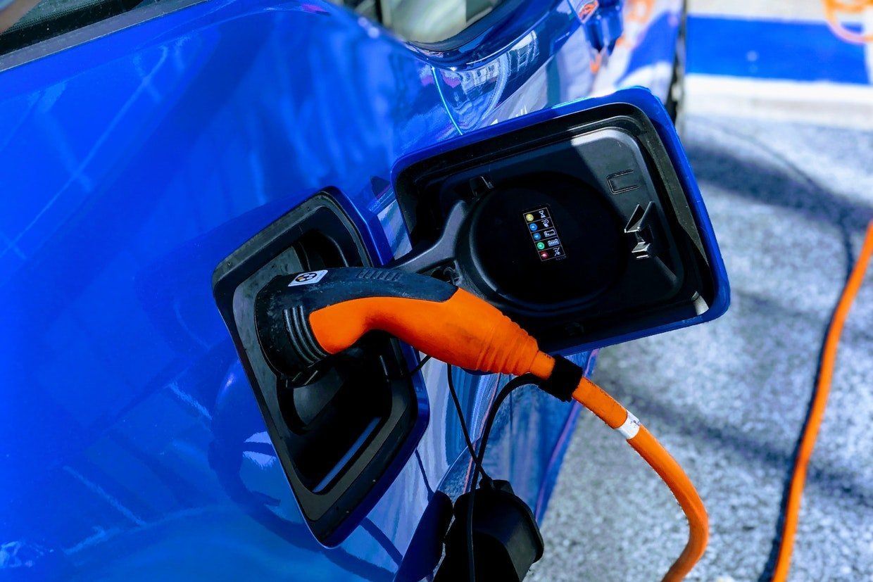 A blue electric car is being charged at a charging station.
