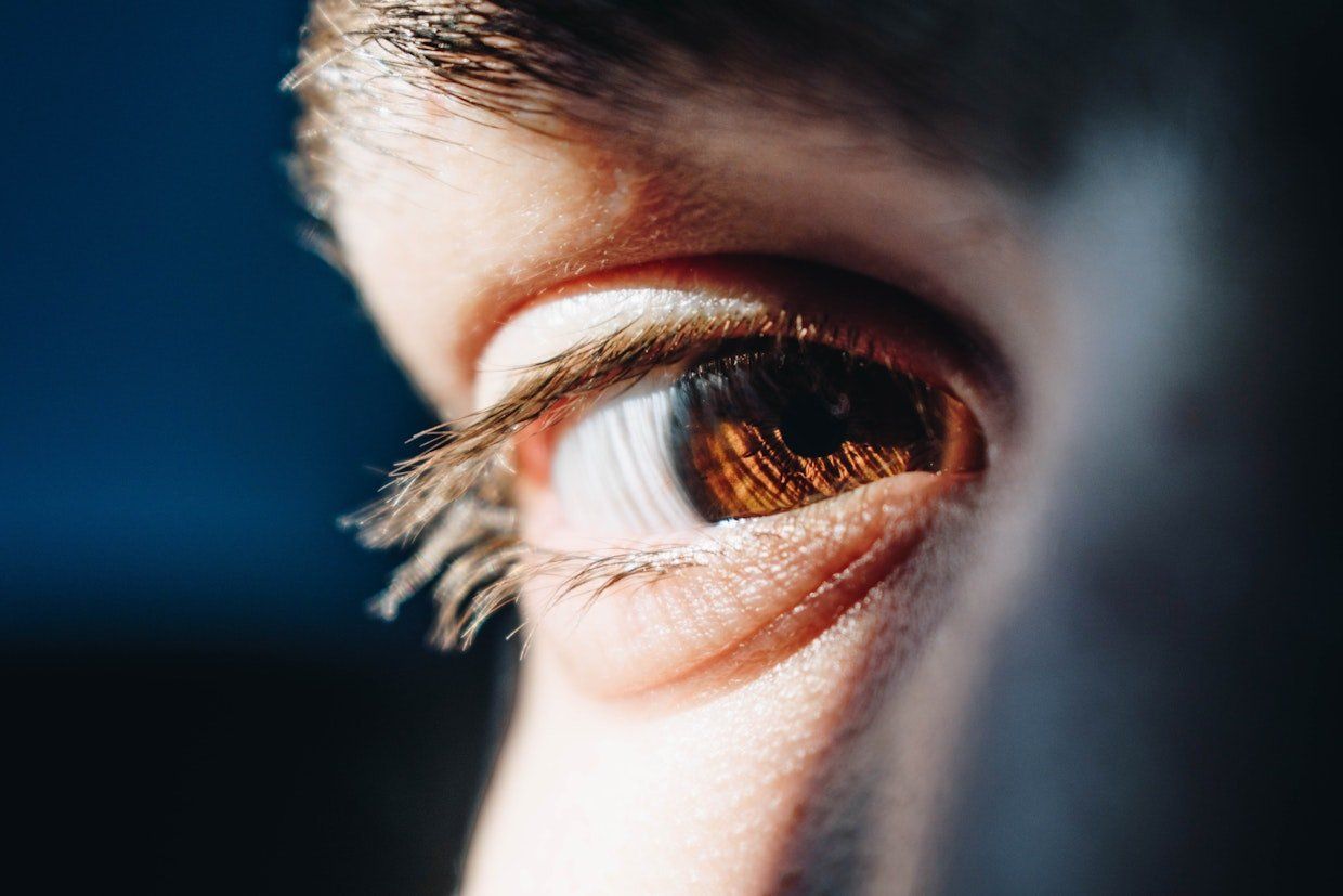 A close up of a person 's eye with a blue background.