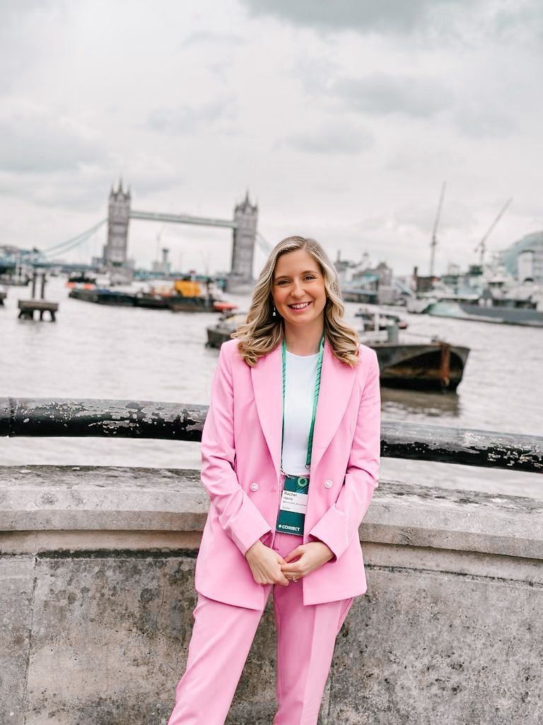 A woman in a pink suit is standing in front of the tower bridge.