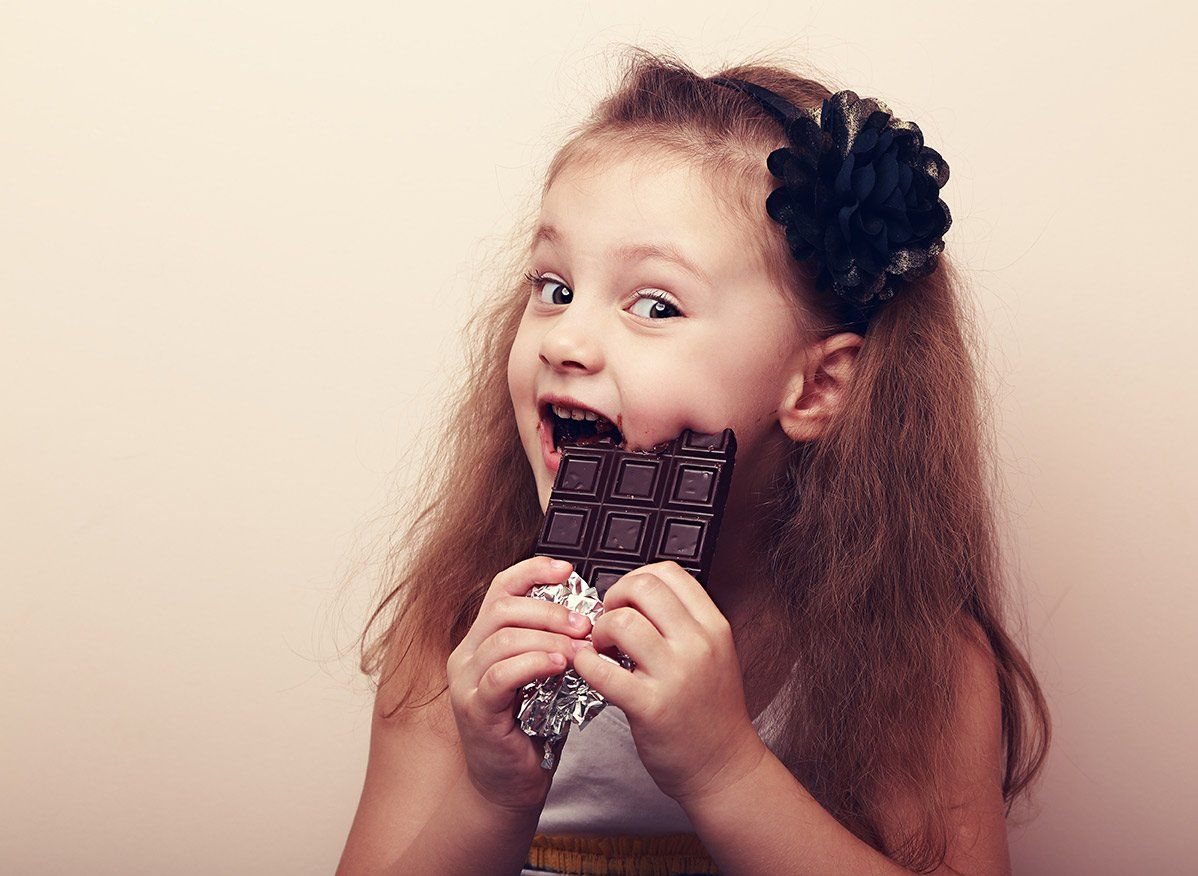 A little girl is eating a chocolate bar.