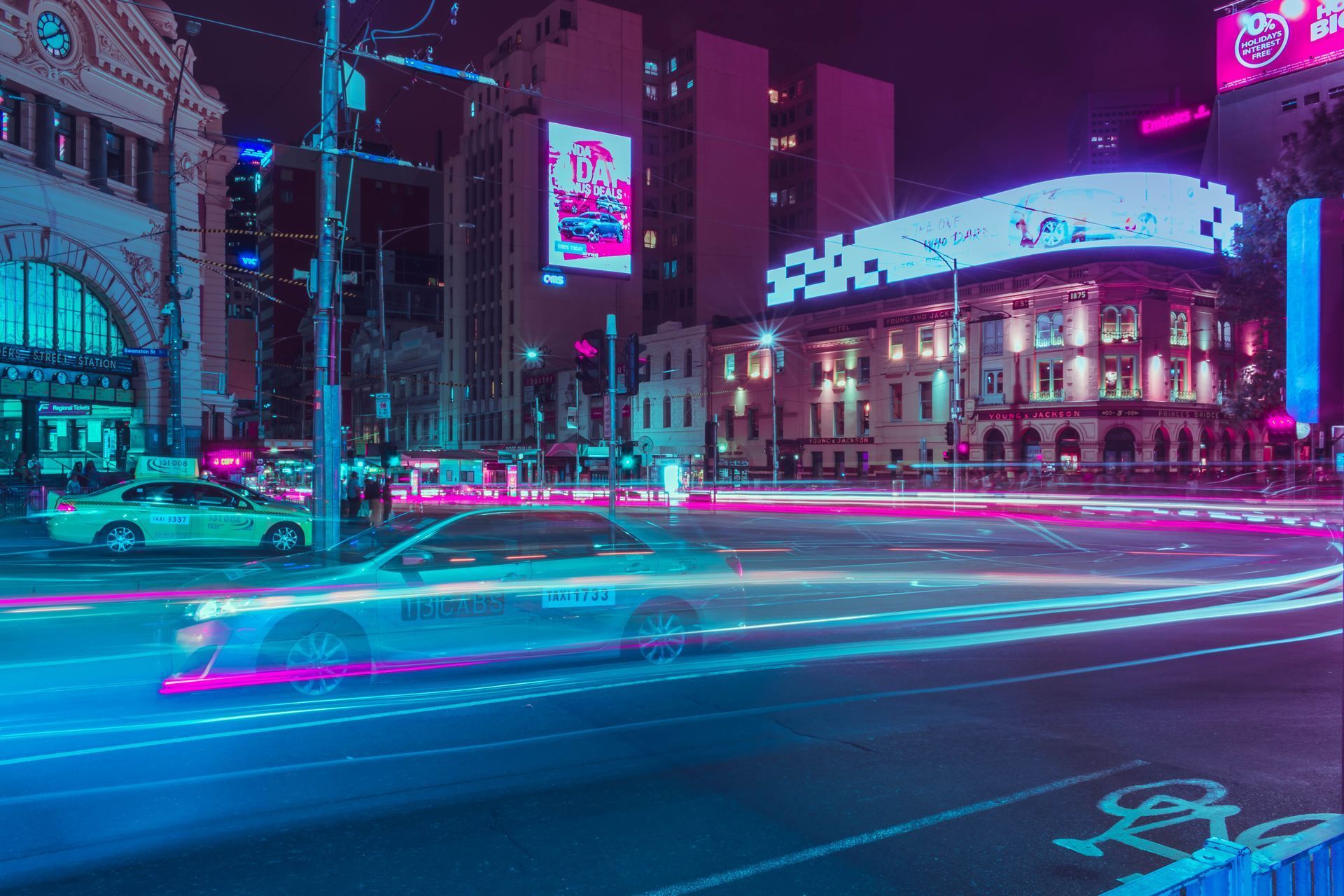 A car is driving down a city street at night.