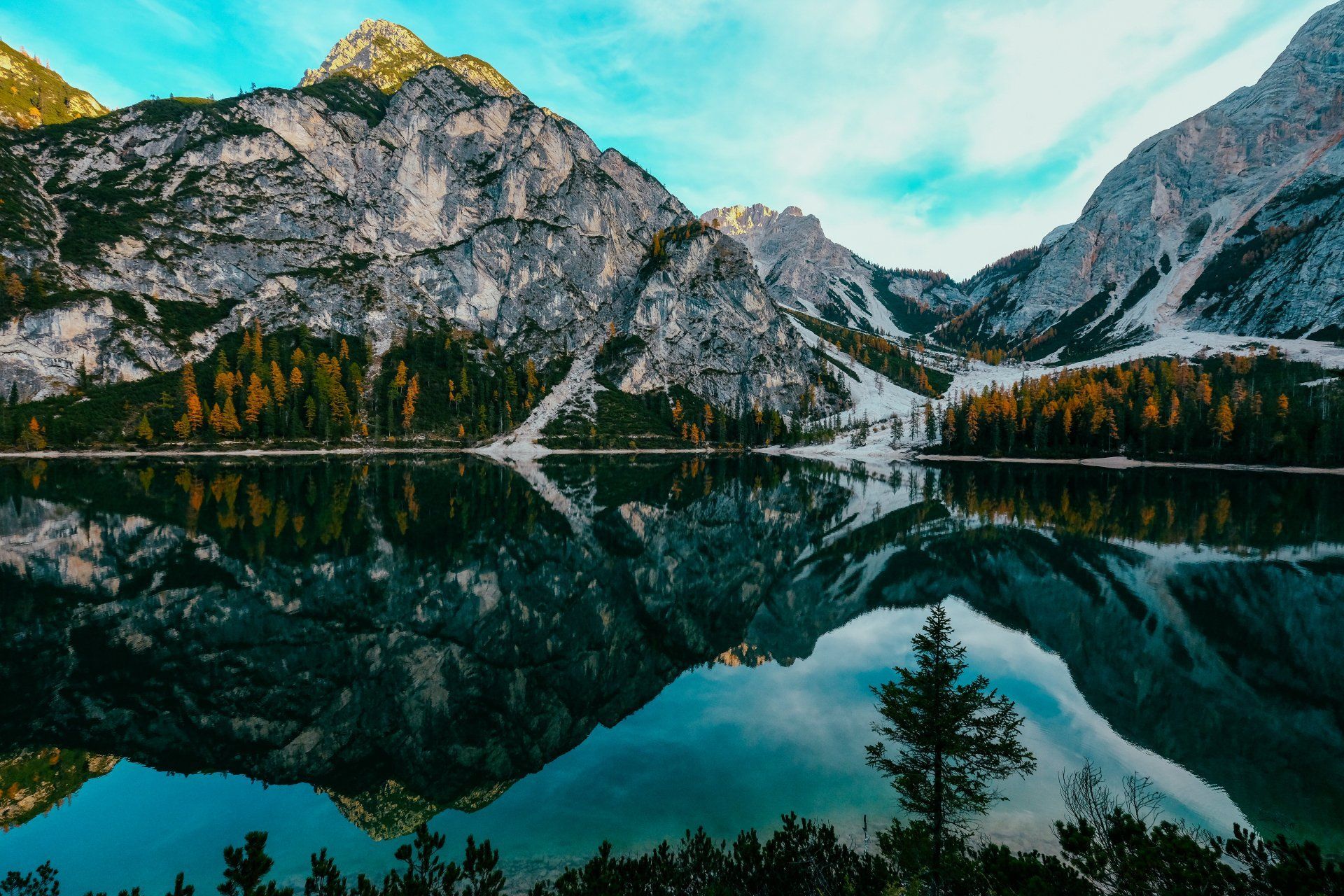 A lake surrounded by mountains and trees is reflected in the water.
