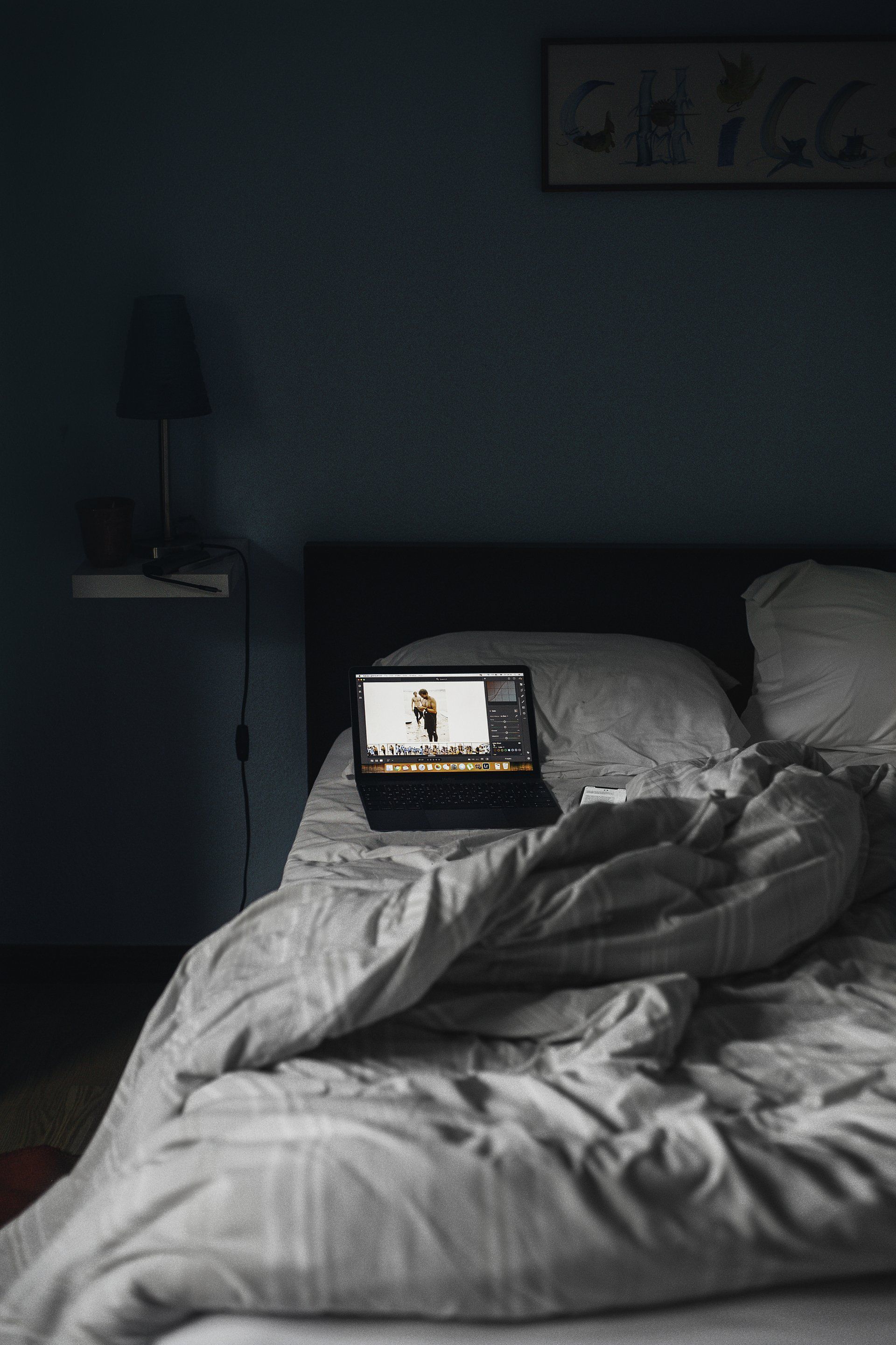 A laptop is sitting on top of a bed in a dark room.