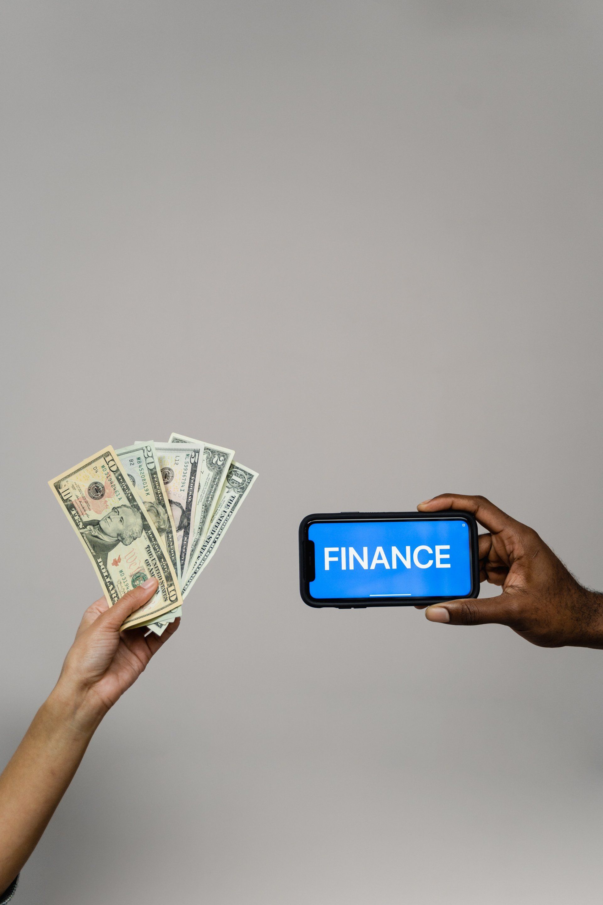 Two people are holding money and a cell phone with the word finance on it.