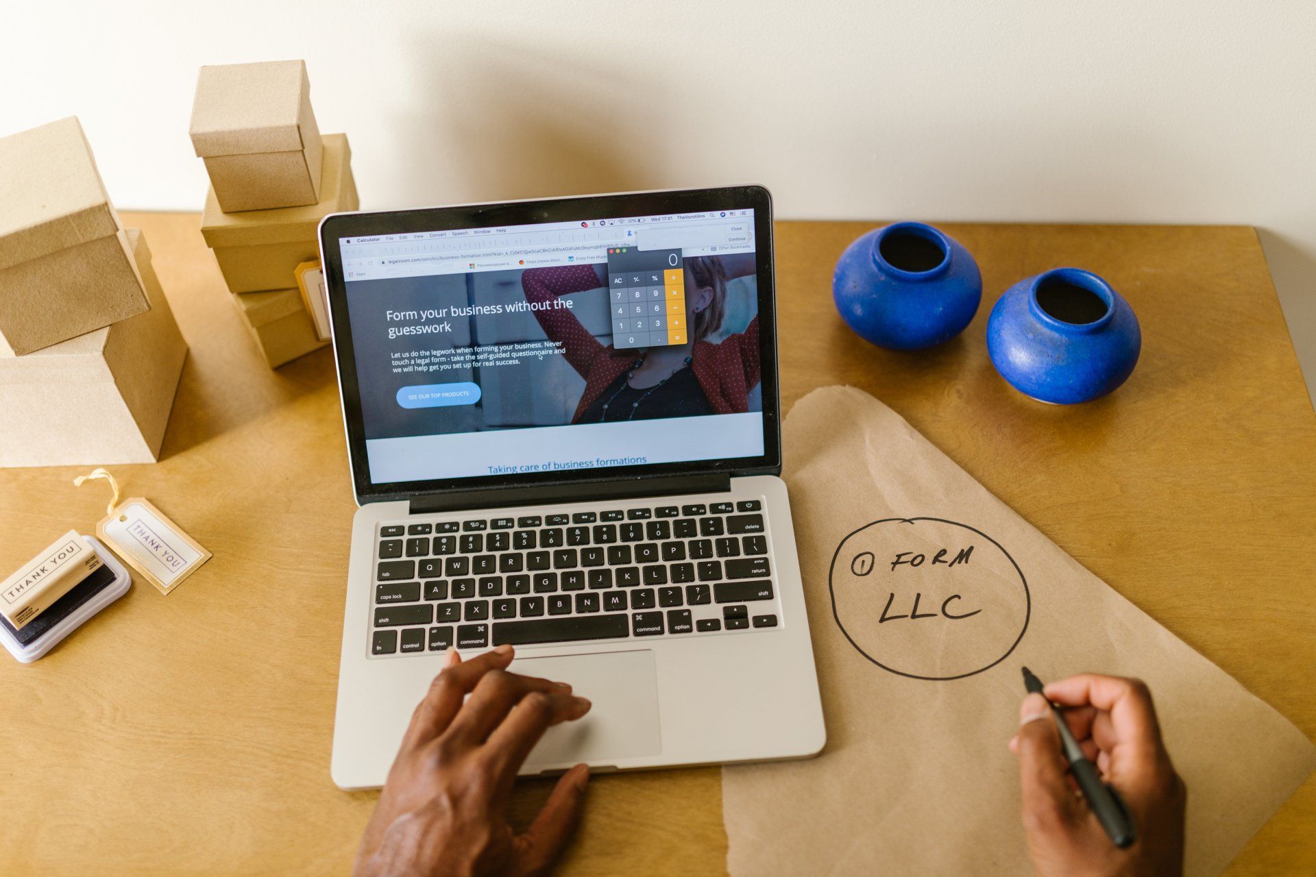 A person is using a laptop computer and writing on a piece of paper.