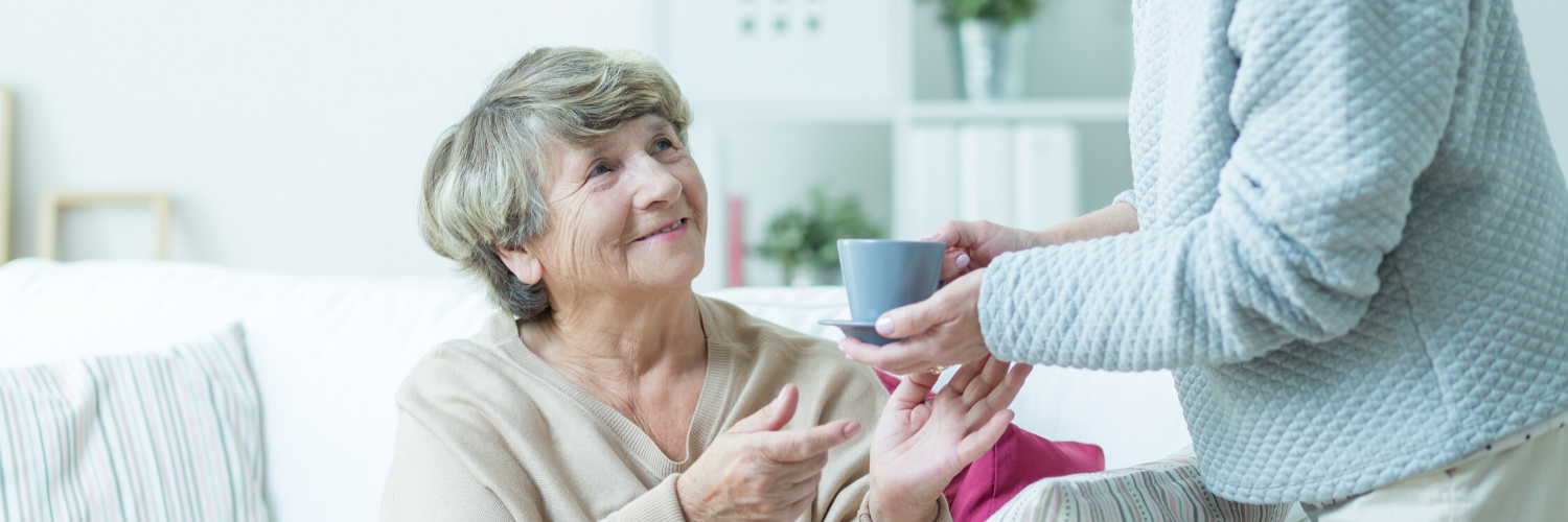 Woman smiling while receiving a cup from another person in a bright room